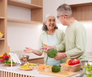 and older woman smiling at an older man while handling vegetables in the kitchen