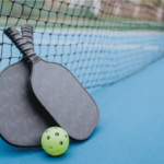 pickleball rackets and a ball next to a net
