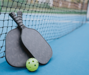 pickleball rackets and a ball next to a net
